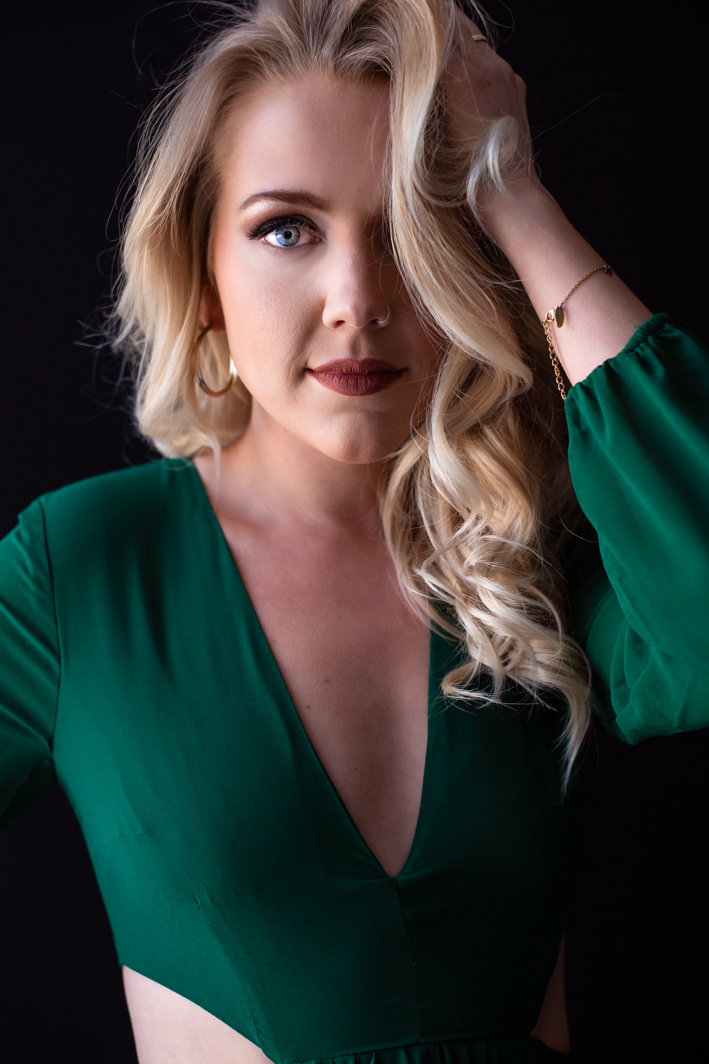 blonde woman in green dress holding her hair